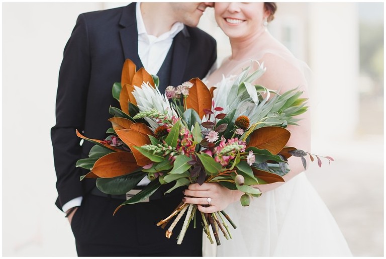 portrait of bride holding unique bouquet with browns and greens