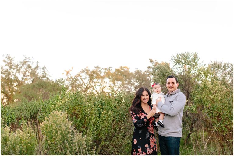 mom and dad pose with one year old daughter